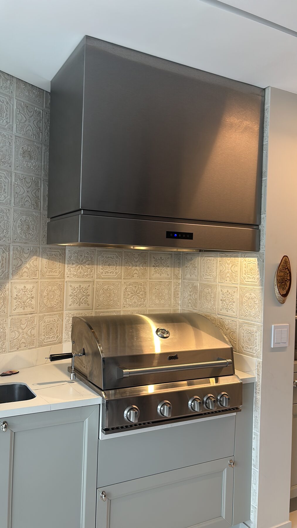 Coifa Box sob medida em aço inox instalada sobre churrasqueira a gás em espaço gourmet