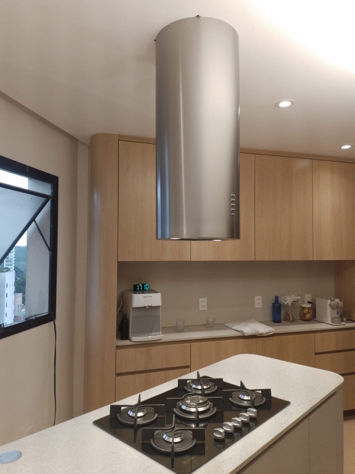Coifa cilíndrica em aço inox instalada sobre ilha em cozinha gourmet