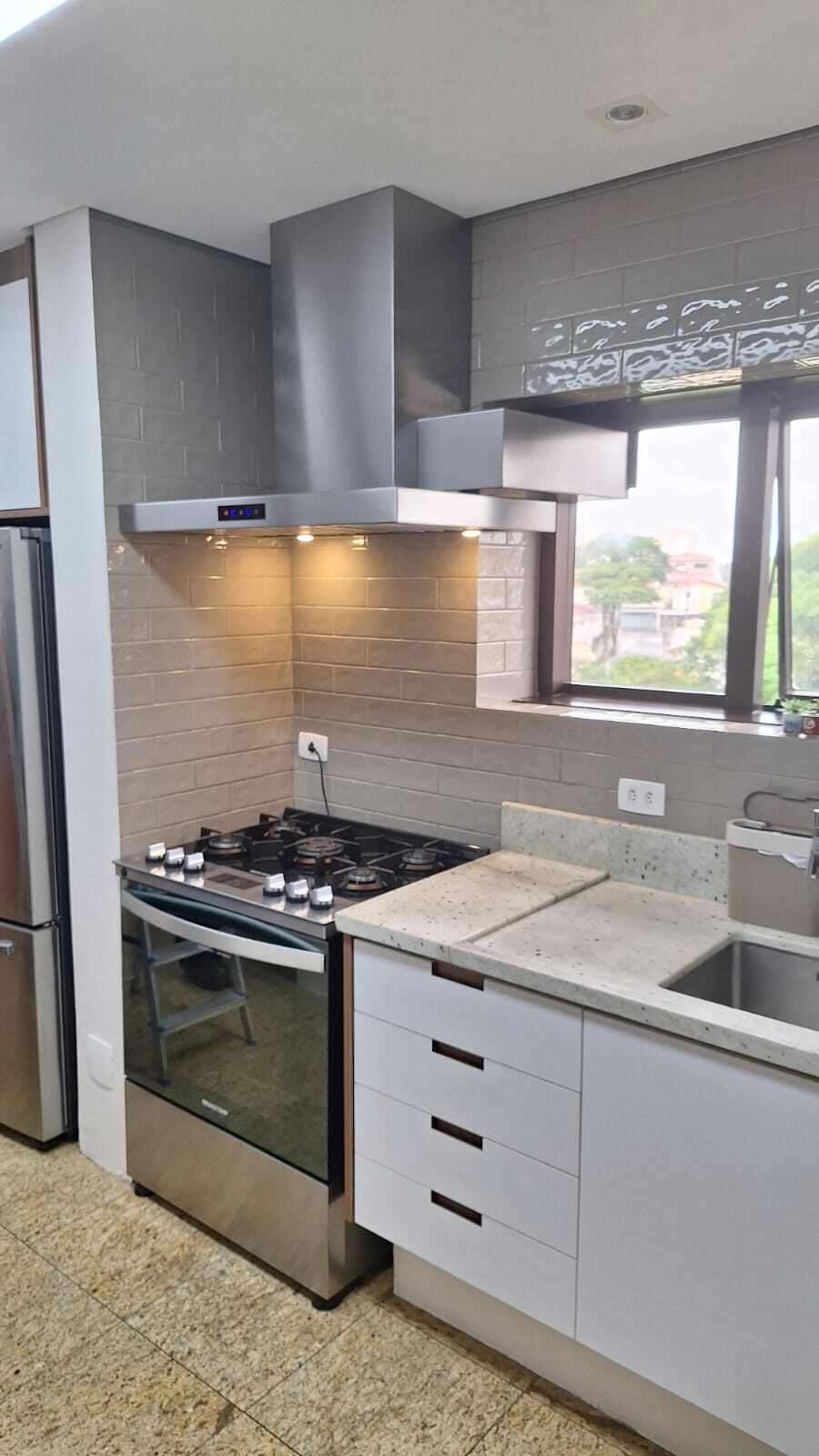 Coifa em aço inox com saída para janela instalada em cozinha gourmet